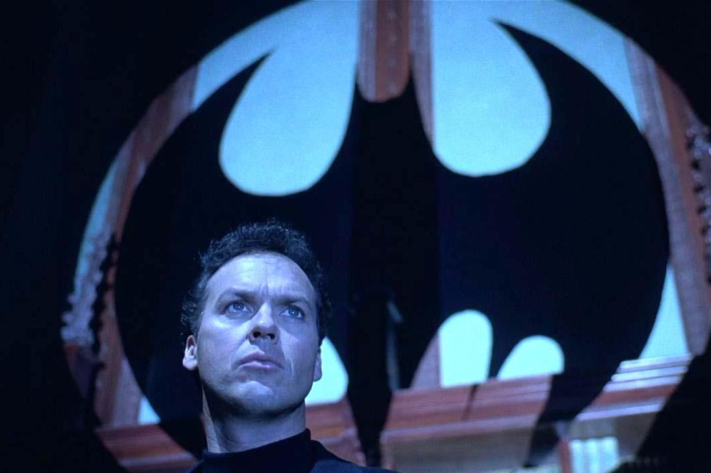 Michael Keaton interprétant Bruce Wayne avec un logo Batman en arrière plan